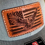 Brown leather patch with eagle and American flag design on a gray cap.