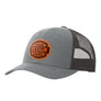 A grey trucker-style cap with a black mesh back and a brown 'your design here' leather patch on the front panel, shown on a plain white background.