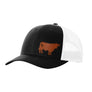 A black trucker-style cap with a white mesh back and a brown cow leather patch on the front panel, shown on a plain white background.
