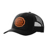 A black trucker-style cap with a black  mesh back and a brown 'your design here' leather patch on the front panel, shown on a plain white background.