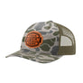 A customizable trucker hat featuring a tan and green camouflage pattern on the front panel and brim, olive green mesh back panels, and an brown circular patch on the front with the text 'YOUR DESIGN HERE'.