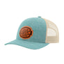 A heathered blue trucker-style cap with a tan mesh back and a brown 'your design here' leather patch on the front panel, shown on a plain white background.