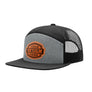 A custom trucker hat with a black flat brim, black mesh back, and a heather gray front panel. The front panel features a circular brown patch with the text 'YOUR DESIGN HERE'.