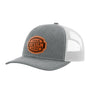 A heathered grey trucker-style cap with a light grey mesh back and a brown 'your design here' leather patch on the front panel, shown on a plain white background.