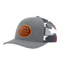 A customizable trucker cap with a heather gray front panel and brim, featuring a brown 'YOUR DESIGN HERE' patch on the front. The back of the cap has a navy mesh back with white stars and red side panels, styled against a plain white background.