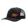 A black trucker hat with a subtle dark gray camouflage pattern on the front panels and brim, featuring a brown leather cow  patch on the side. The back is made of black mesh, on a white background. 