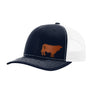 A navy blue trucker hat with white mesh back, a brown cow leather patch on the front panel, shown against a plain white background.