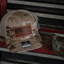 Camouflage trucker cap with American flag leather patch on a metal tool bench