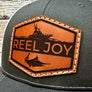 Gray cap with a brown leather patch featuring 'Reel Joy' and a fishing design.