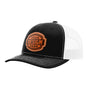 A black trucker-style cap with a white mesh back and a brown 'your design here' leather patch on the front panel, shown on a plain white background.